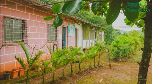 a pink house with plants in front of it at Devraai Homestay 