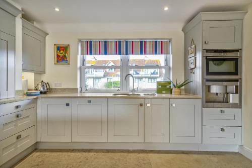 a kitchen with white cabinets and a window at Shore View - East Wittering in East Wittering