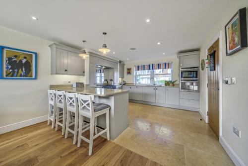 a kitchen with white cabinets and a island with bar stools at Shore View - East Wittering in East Wittering