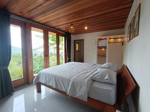 a bedroom with a large bed and a large window at Sonnenhouse Lombok Kertaraharja in Luk