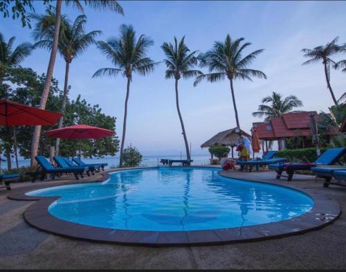 a large swimming pool with palm trees and the ocean at Phangan Beachside Villa in Ban Tai