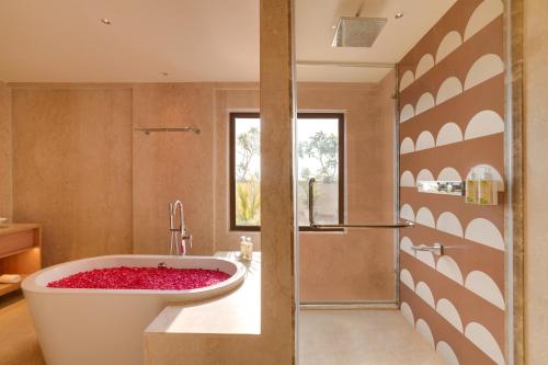 a bathroom with a large tub with red flowers in it at Lemon Tree Premier, Thiruvananthapuram in Trivandrum