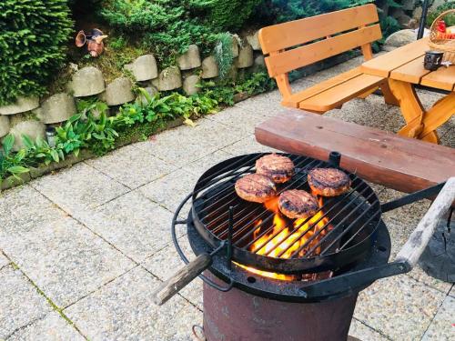 a grill with hamburgers on it next to a bench at Apartments in Harrachov - Riesengebirge 2300 in Harrachov