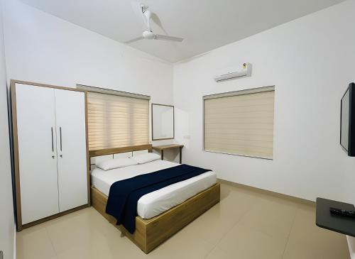 een slaapkamer met een bed en een flatscreen-tv bij Easy Nest Residency in Kannur