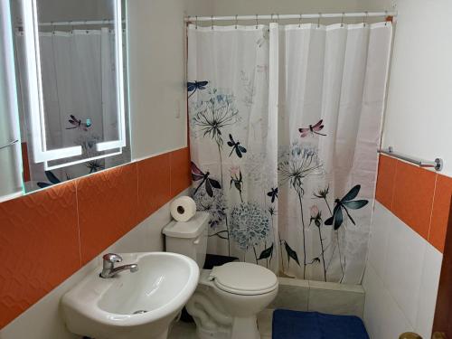 a bathroom with a toilet and a sink and a shower curtain at LibiMar in Manta