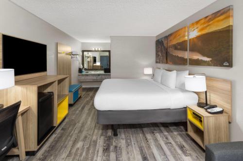 a hotel room with a bed and a flat screen tv at Days Inn by Wyndham Branson Ozarks in Branson