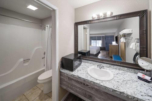 a bathroom with a sink and a toilet and a mirror at Days Inn by Wyndham Branson Ozarks in Branson