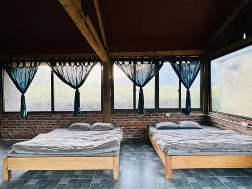 two beds sitting in a room with windows at Giay's Local House in Sapa