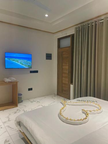 een slaapkamer met een bed en een tv aan de muur bij Wish Maamigili in Maamigili