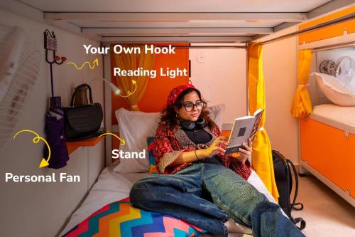 a woman sitting on a bed with a laptop at goSTOPS Coorg in Madikeri