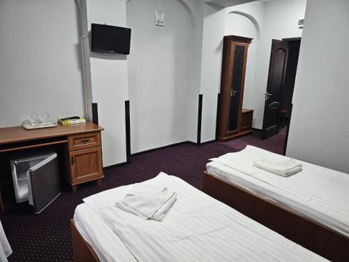 フォクシャニにあるHotel Ambasadorのベッド2台とテレビがあるホテルの部屋