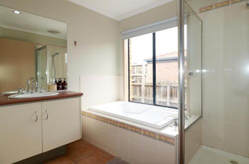 a bathroom with a shower and a sink and a window at Sweet Home at Carrum Downs in Carrum Downs