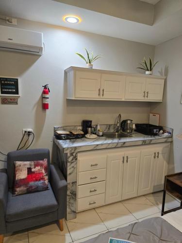 a kitchen with a counter and a sink and a chair at El Rincón - El Jardín in Tunapuna