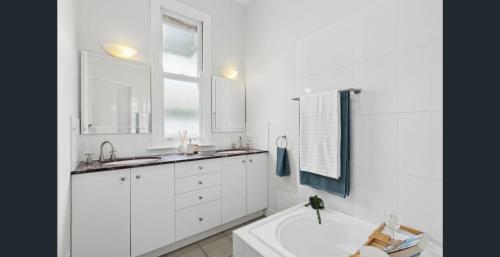 a white bathroom with a tub and a sink at Parkside Family Haven - 5bdrm in Brisbane