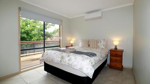 a bedroom with a bed and a large window at Sweet Home at Carrum Downs in Carrum Downs