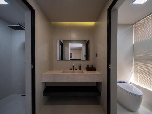 a bathroom with a sink and a toilet and a mirror at Lijiang Ancient City Hitone Rizhao Jinshan Sky Garden Snow Mountain Viewing Resort in Lijiang
