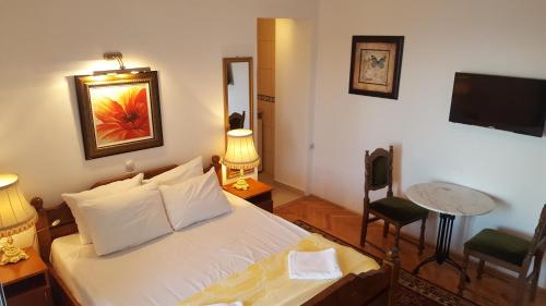 een slaapkamer met een bed, een tafel en een televisie bij Apartments Maestro in Ulcinj