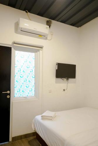 a bedroom with a bed and a television on the wall at Puspiptek Residence Syariah in Curug 3