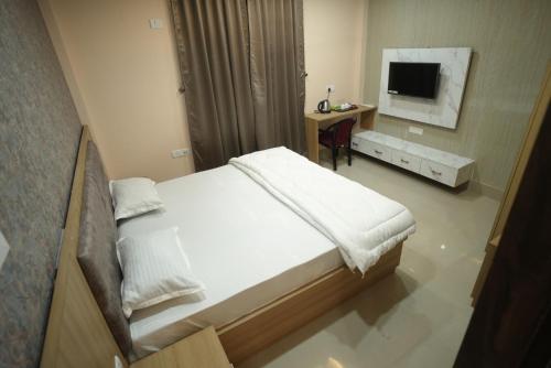 a bedroom with a large bed and a television at Aroma Homes in North Lakhimpur