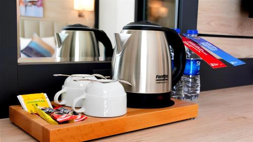 a coffeemaker sitting on a shelf with two coffee pots at Ramada Encore By Wyndham Istanbul Basin Express in Istanbul