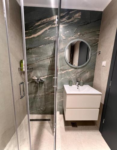 een badkamer met douche, wastafel en spiegel bij Apartment Voulas 3 in Ptolemaida