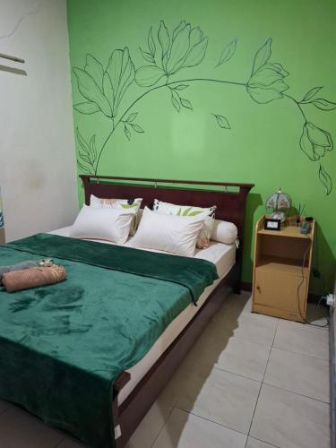 a bedroom with a bed with a green wall with leaves on it at Rumah Bapak in Yogyakarta
