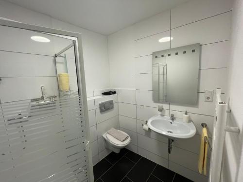 a white bathroom with a toilet and a sink at Herr Berge in Fritzlar