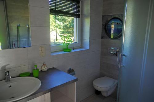 a bathroom with a sink and a toilet and a window at Wypoczynkowa Osada domki blisko morza in Jastrzębia Góra