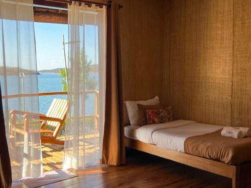 a bedroom with a bed and a view of the ocean at TSIAZOMPANIRY ISLAND LODGE in Ambohimiadana