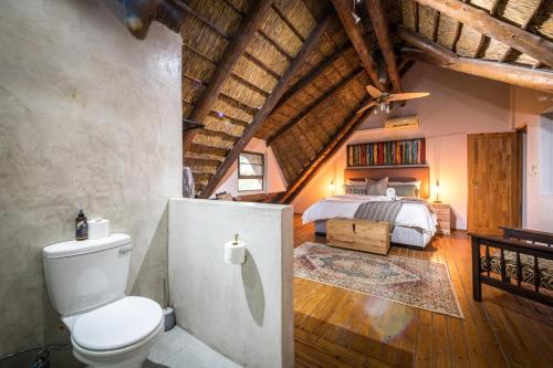 a bedroom with a bed and a toilet in a room at Nzenga Lodge in Hoedspruit