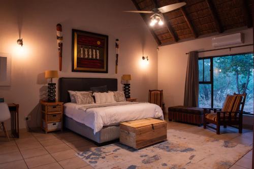 a bedroom with a bed and a large window at Nzenga Lodge in Hoedspruit
