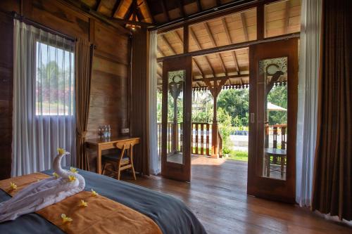 a bedroom with a bed and a desk and sliding glass doors at Pondok Tegal Tunon Villa Ubud Bali in Ubud