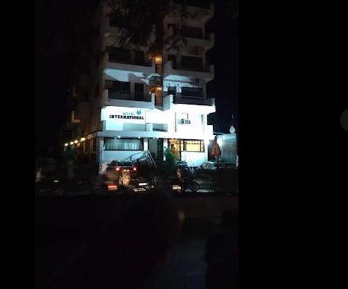 a tall white building at night with at Hotel International, Kolhapur in Kolhapur