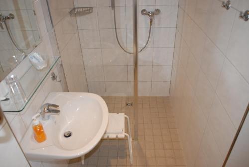 ein Bad mit einem Waschbecken und einer Dusche in der Unterkunft Gasthof Brinkmeier in Lippstadt