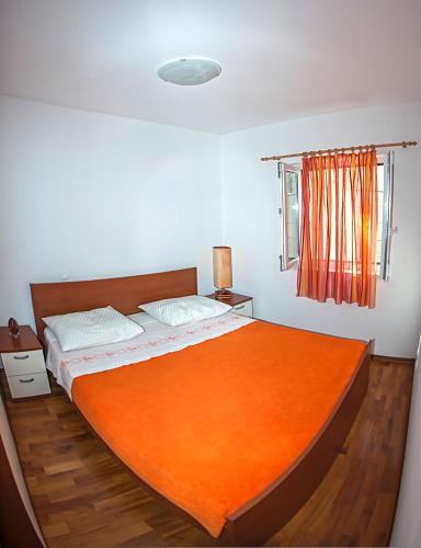 a bedroom with a large bed with an orange blanket at Apartment Brač in Sutivan
