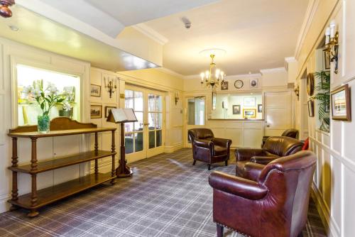 una sala de espera con sillas de cuero y un piano en Bridge Hotel, en Buttermere