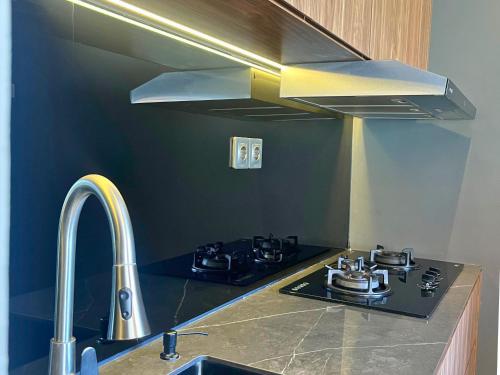 a kitchen with a stove and a stainless steel hood at Kana Suites Jimbaran By Fays Hospitality in Nusa Dua