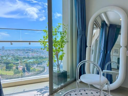 a white chair in a room with a large window at The Song Apartment 5 Stars Vung Tau - Căn Hộ Du Lịch 5 Sao Cạnh Biển - DUMIN HOMESTAY in Vung Tau