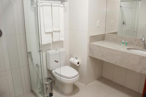 a white bathroom with a toilet and a sink at Gran Park Hotel e Convenções in Mineiros