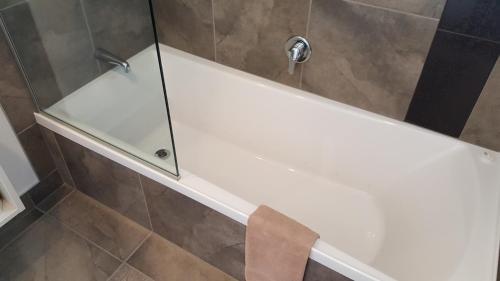 a shower with a glass door on a tub at Rose City Motel in Palmerston North