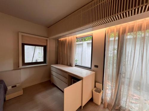 um pequeno quarto com uma secretária e 2 janelas em Tree Villa Bangkok em Banguecoque