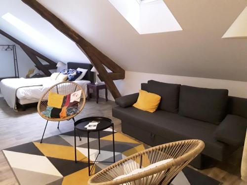 Una sala de estar con un sofá y sillas y una cama. en La Pomme d'Or, en La Charité-sur-Loire