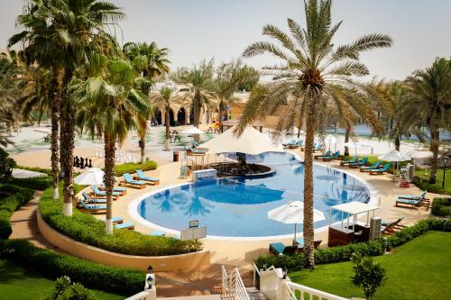 an aerial view of a resort pool with palm trees at Metropolitan Al Mafraq Hotel in Abu Dhabi