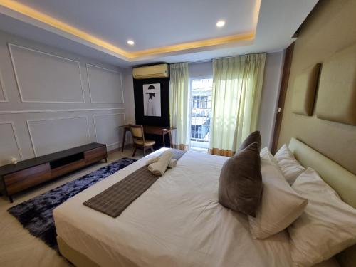 Un dormitorio con una gran cama blanca con ventana. en RB9 Oliver's House in Kaset, en Ban Yang