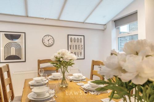 a dining room with a wooden table with white flowers at Fit for a King-size Nap I Parking in Windsor