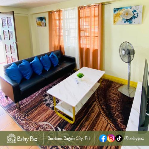 a living room with a black couch and a table at Spacious 2BR Family Home - Narra Unit by Balay Paz in Baguio