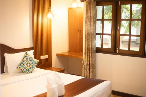 a hotel room with a bed and a window at CleanWave Resort Chumphon คลีนเวฟ รีสอร์ท in Thung Wua Laen Beach