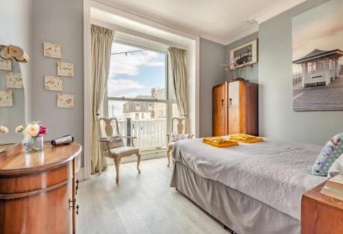 een slaapkamer met een bed, een bureau en een raam bij Ocean view in Swanage