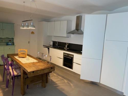 a kitchen with a wooden table and a kitchen with white cabinets at Casa Emma in Monteggio