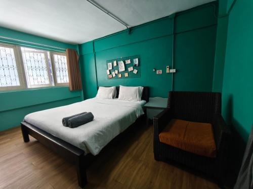 a bedroom with green walls and a bed and a chair at Hello House in Krabi town